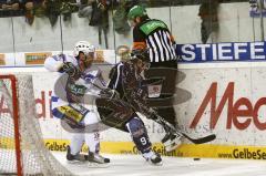 Bob Wren im Zweikampf hinter dem Tor gegen Dylan Gyori (weiss). Der Schiedsrichter springt zur eigenen Sicherheit hoch.  Aufgenommen im Spiel zwischen ERC Ingolstadt und EHC München in der Ingolstädter Saturn Arena am 20.02.2011. Endstand 2:3 nach Penalty