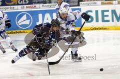 Wyatt Smith (blau) zeigt vollen Körpereinsatz gegen Rene Kramer (weiss). Sogar im Flug kämpft er um die Scheibe. Aufgenommen im Spiel zwischen ERC Ingolstadt und EHC München in der Ingolstädter Saturn Arena am 20.02.2011. Endstand 2:3 nach Penaltyschiesse