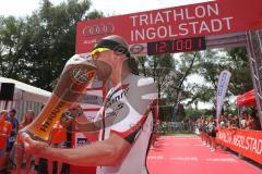 Triathlon Ingolstadt 2015 - Baggersee - Olympische Distanz, Ziel Einlauf, Emotion, Sieger Per Bittner (Leipzig) Jubel, Organisator überreicht das Bierglas